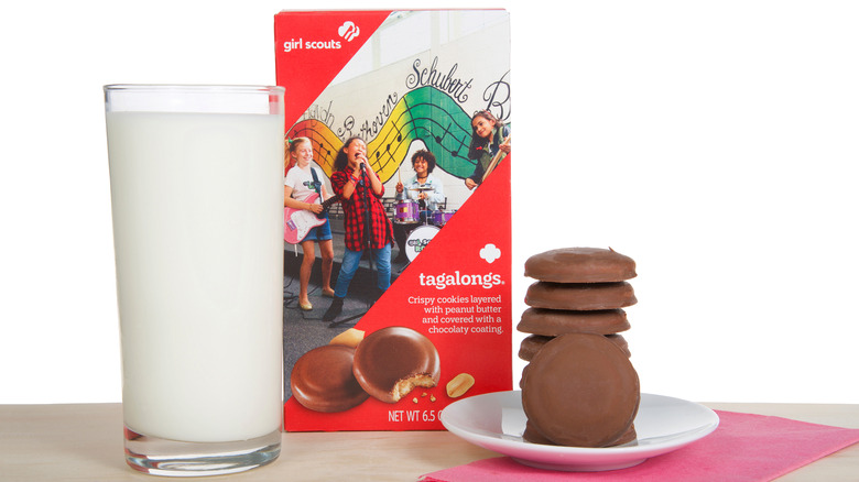 a box of tagalongs next to a plate of peanut butter patties with a glass of milk girl scout cookies