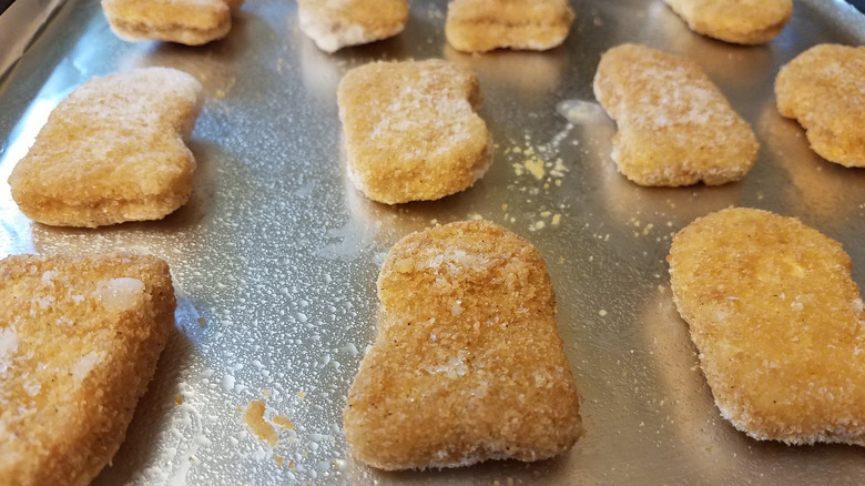 Frozen chicken nuggets on baking sheet