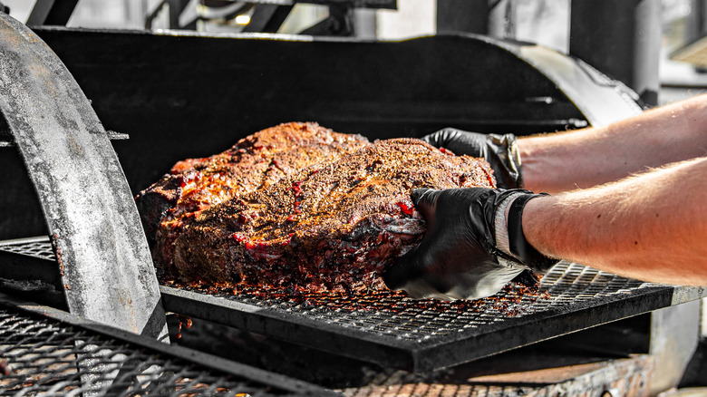 inserting meat into a grill smoker