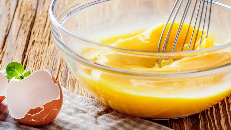 eggs in bowl with shells and whisk