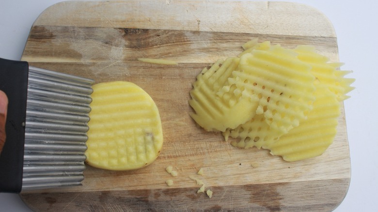 Potatoes cut for waffle fries on a cutting board