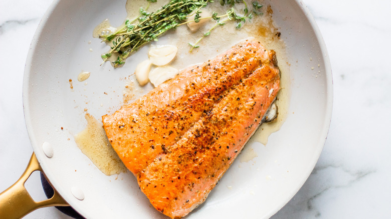 salmon in pan with herbs and garlic