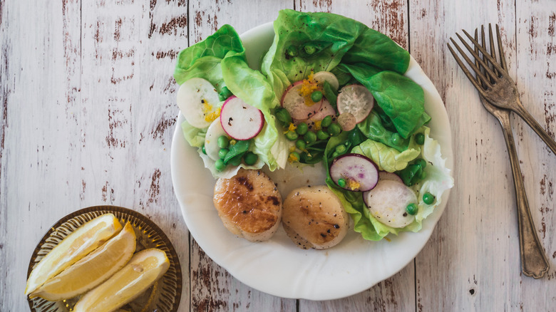 plate with salad and scallops, and small bowl with lemons