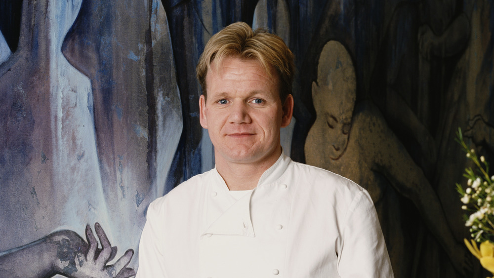 Gordon Ramsay in chef's whites standing in front of painting