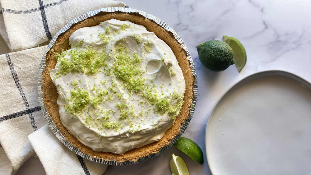 5-ingredient key lime pie in pastry shell with white plate and limes