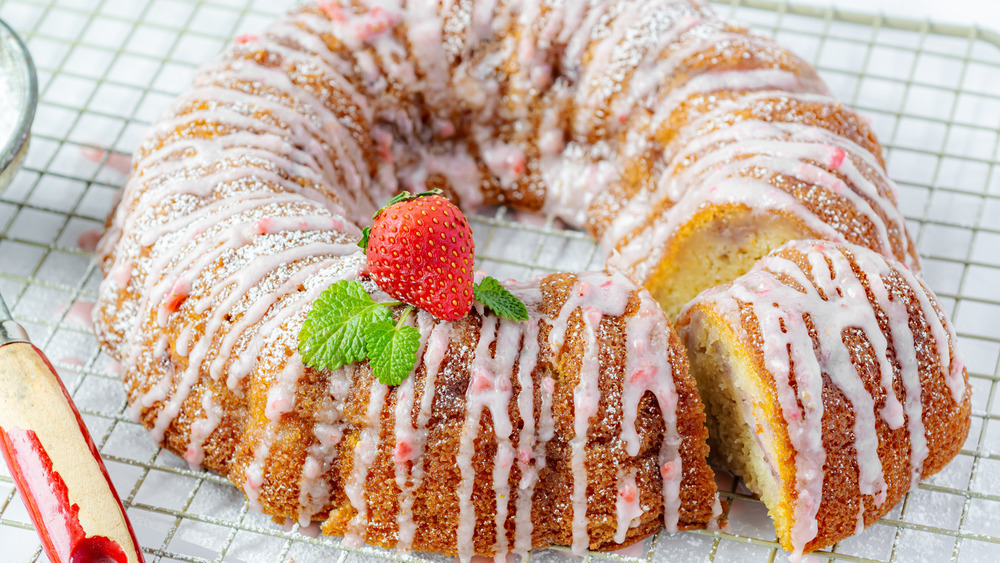 Strawberry cake on wire rack with a fresh strawberry