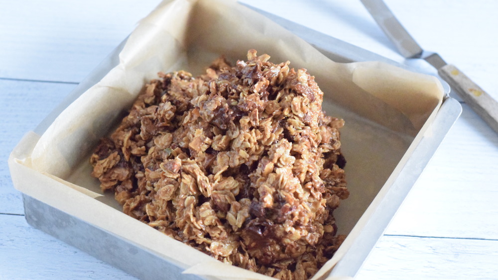 granola bar mixture being added to square pan