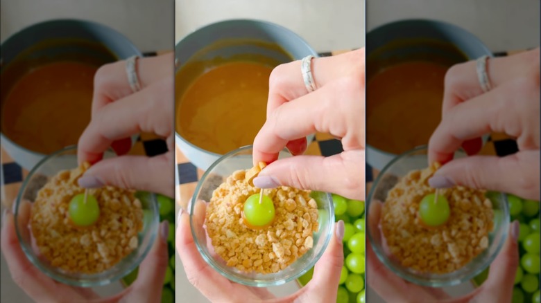 Dipping caramel-dipped grape in peanuts