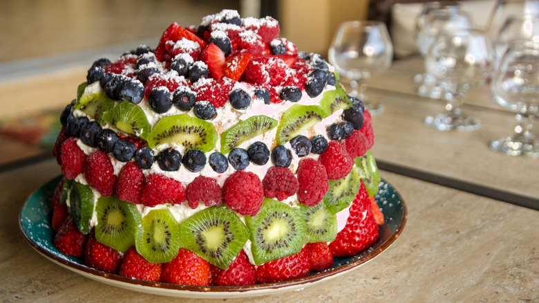 Round cake decorated with fresh fruit on plate