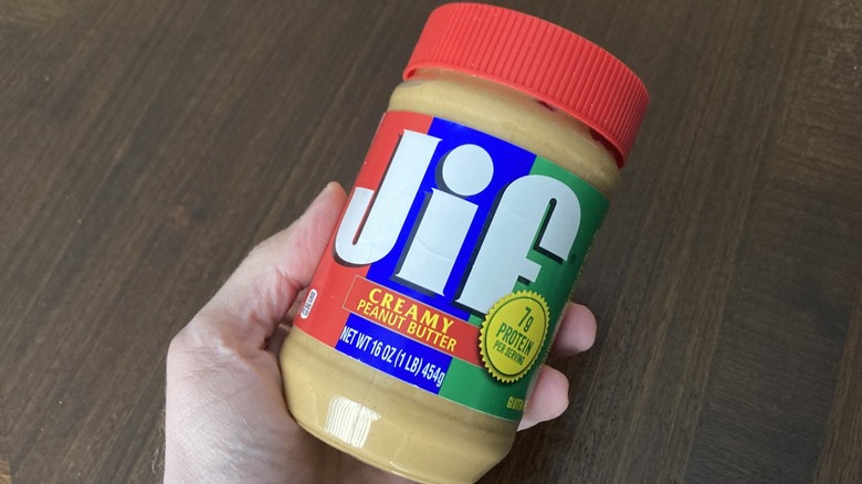 Hand holding a jar of Jif