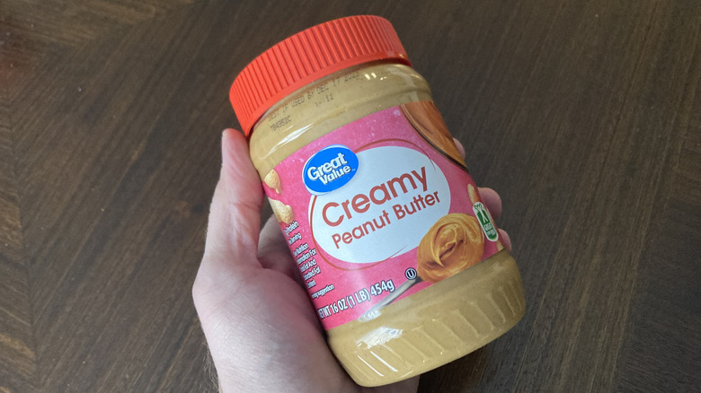 Hand holding Great Value peanut butter