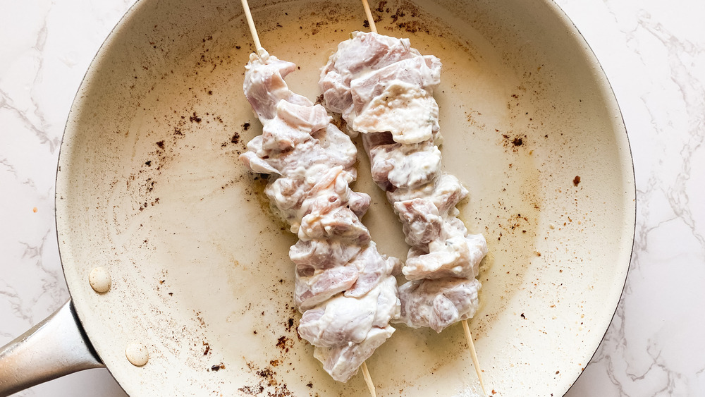 Greek chicken souvlaki skewers in a pan