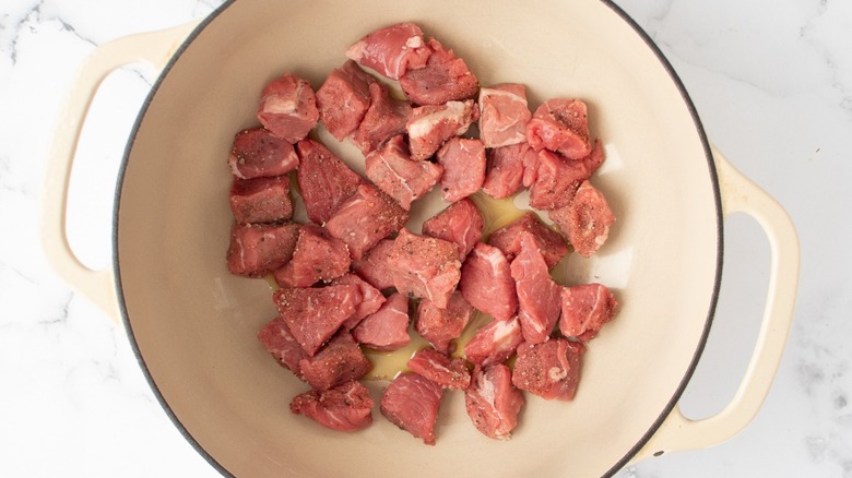 raw beef pieces in pot