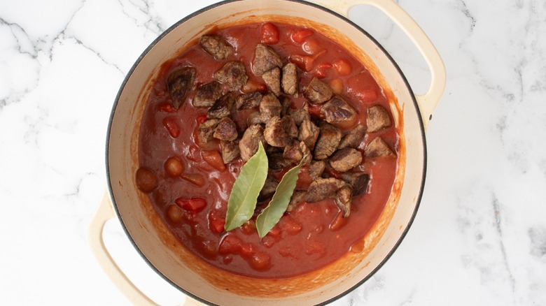 beef, bay leaves, and tomatoes in pot