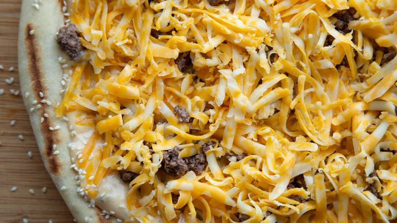 cheese and ground beef on pizza before cooking