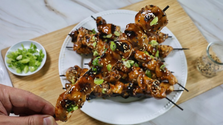 hand holding grilled sesame chicken skewer