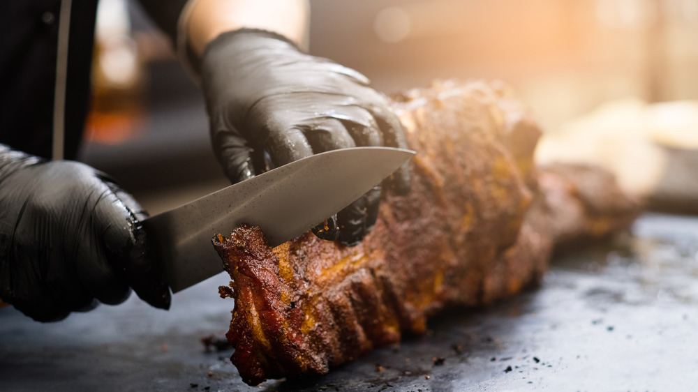 Barbecue chef cutting ribs with black gloves