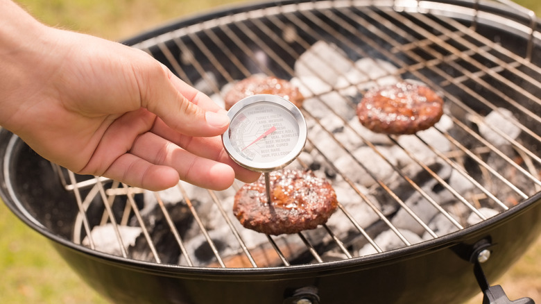 Meat thermometer and burgers on grill