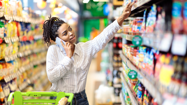 Woman reaching top grocery shelf