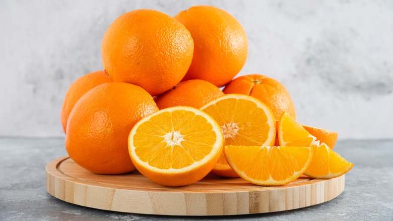 A pile of whole and sliced oranges