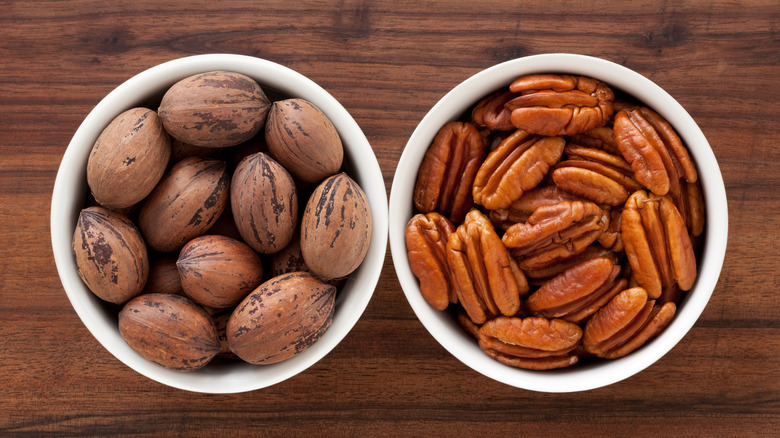 Two bowls of unshelled and shelled pecans