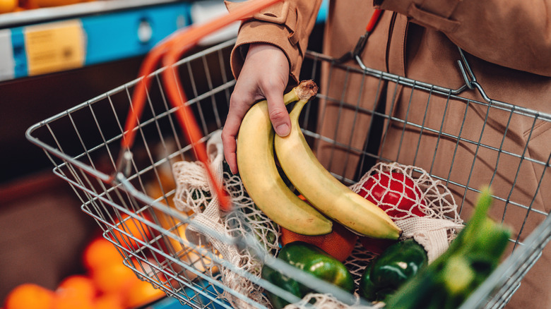 person adding bananas to grocery basket