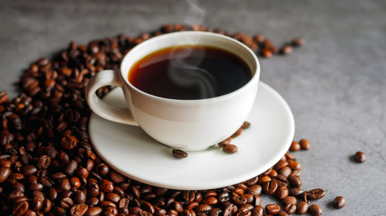 Steaming cup of coffee with beans