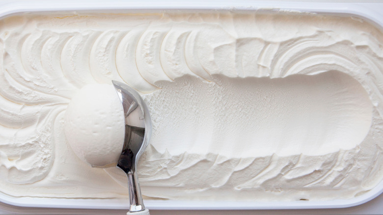 An ice cream scoop forming a ball of vanilla ice cream