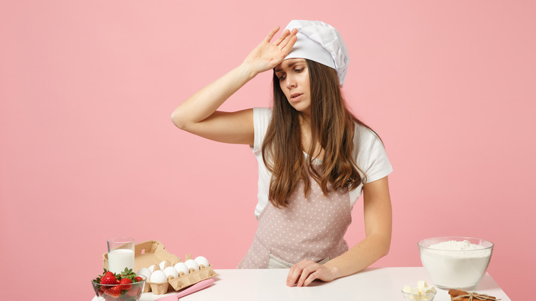 woman in a chef outfit looking tired and sick