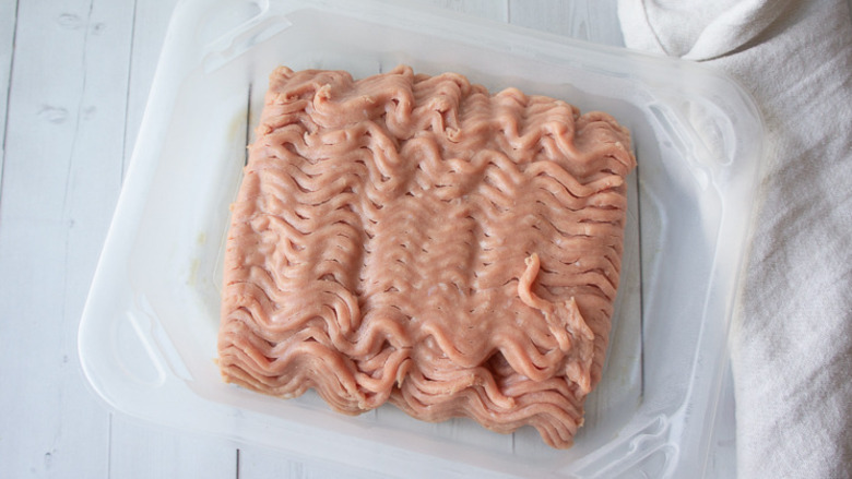 a pound of ground turkey in a container on a white table