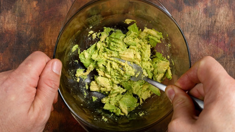 Person mashing gucamole in a bowl