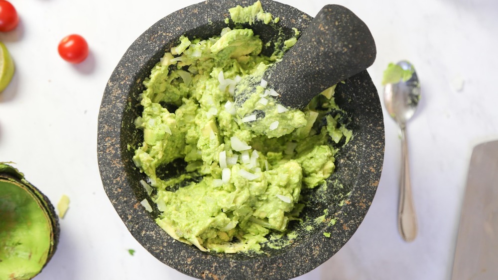 Adding onions to avocado for guacamole