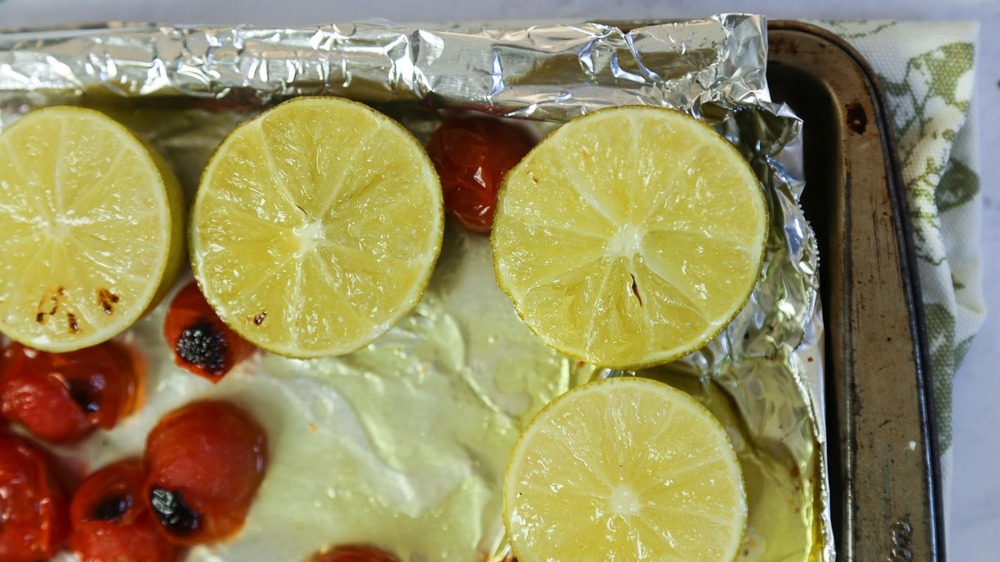 Limes and tomatoes on baking sheet for guacamole