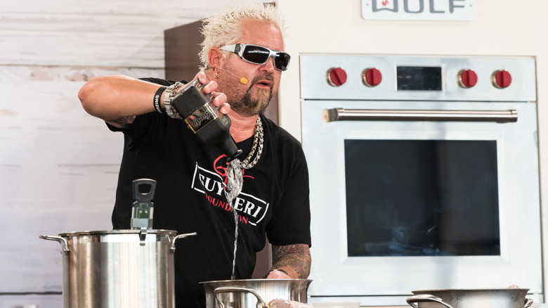 Guy Fieri pouring liquid into pot on stove