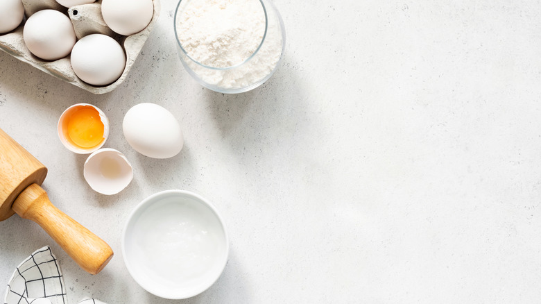 Flour and eggs on a counter with a rolling pin.