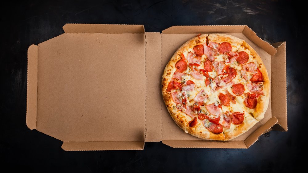 Pizza in a delivery box on black background