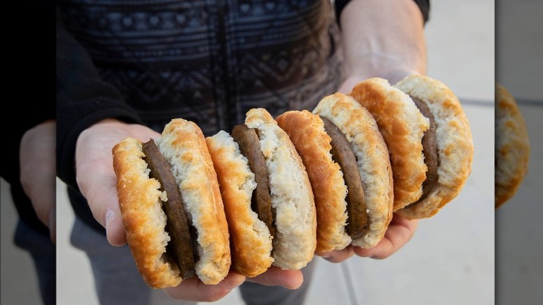 holding sausage biscuits sandwiches