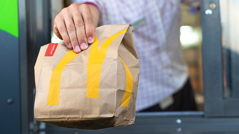 A McDonald's employee handing over a bagged meal