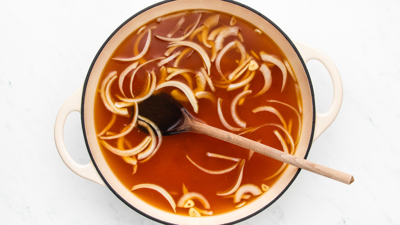 Chicken broth, sliced onions, and garlic in casserole pot