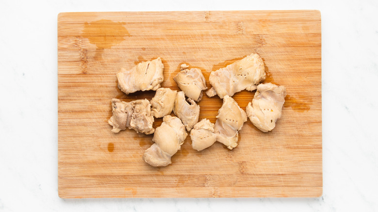 Cooked chicken thighs on wooden cutting board