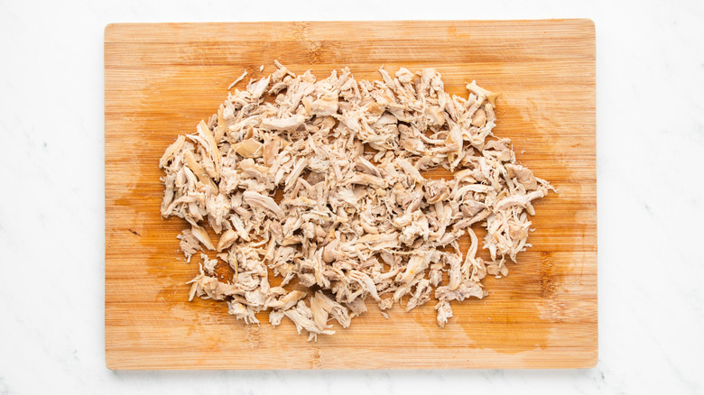 Shredded chicken on wooden cutting board