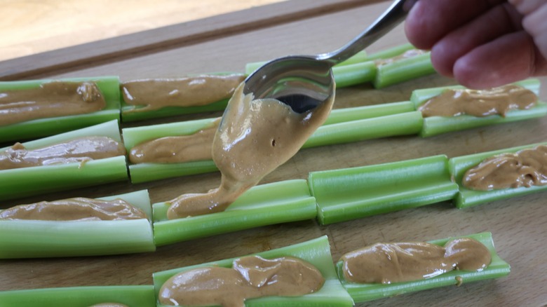 spooning peanut butter into celery