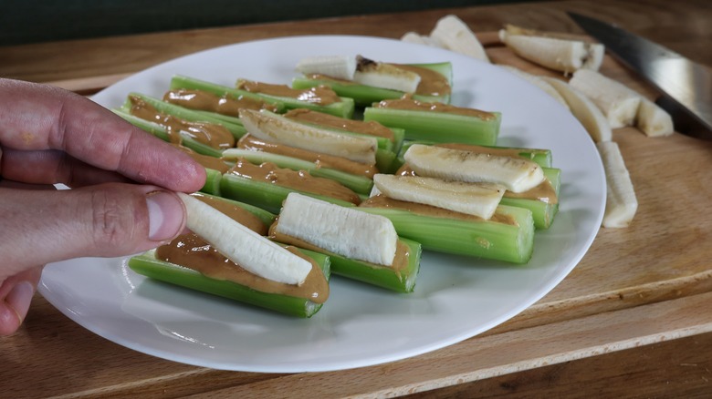 adding bananas to celery with peanut butter