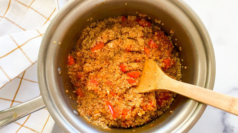 Finished quinoa Spanish rice in metal pot with wooden spoon