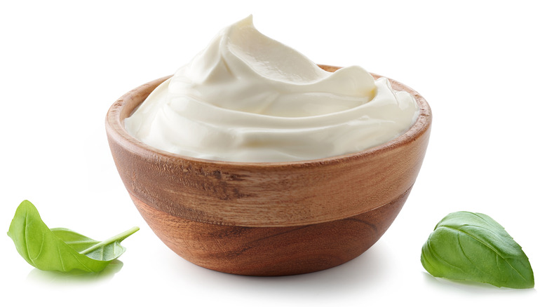 Bowl of plain Greek yogurt with basil leaves.