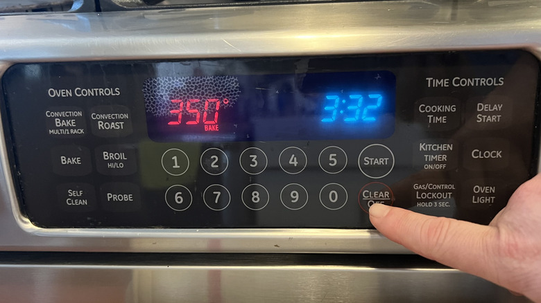 Hand touching oven temperature gauge