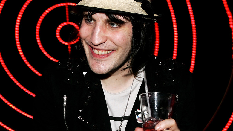 Noel Fielding holding drink with red light background