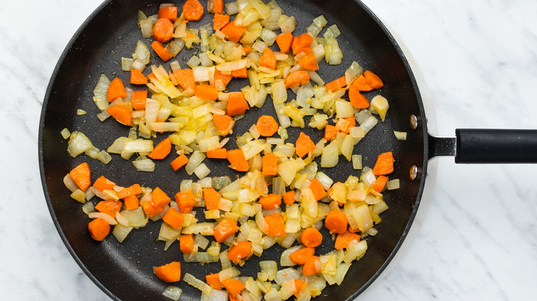 Carrots, onions and garlic cooking in a frying pan