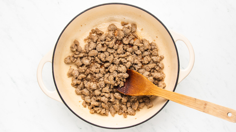 Sausage meat cooking in casserole pot