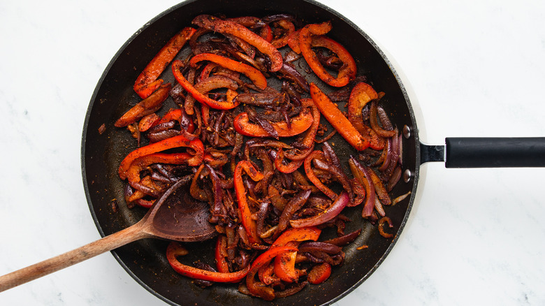 Onion, pepper and spices frying in pan